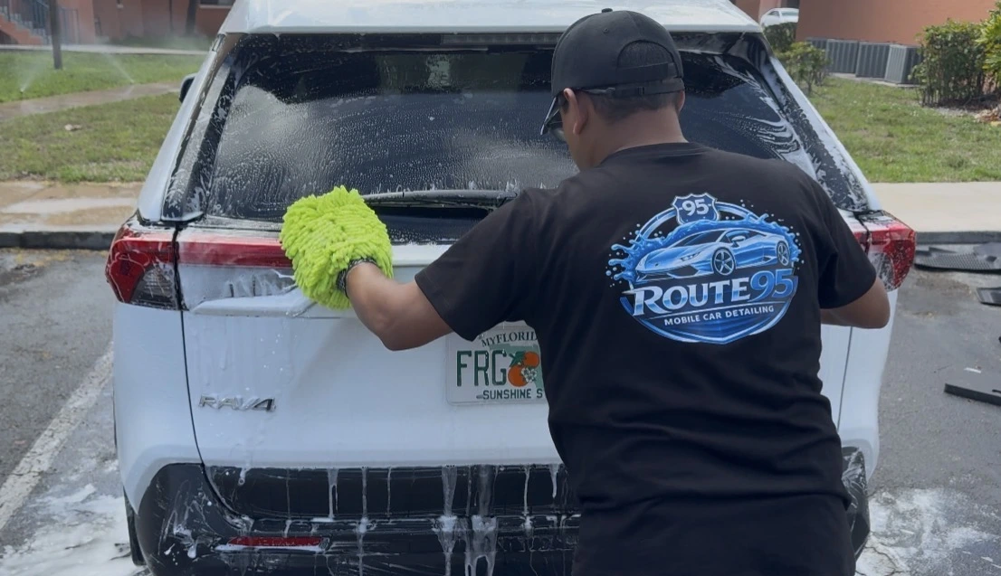 Route95 detailer hand washing a white SUV with a microfiber wash mitt in Fort Lauderdale